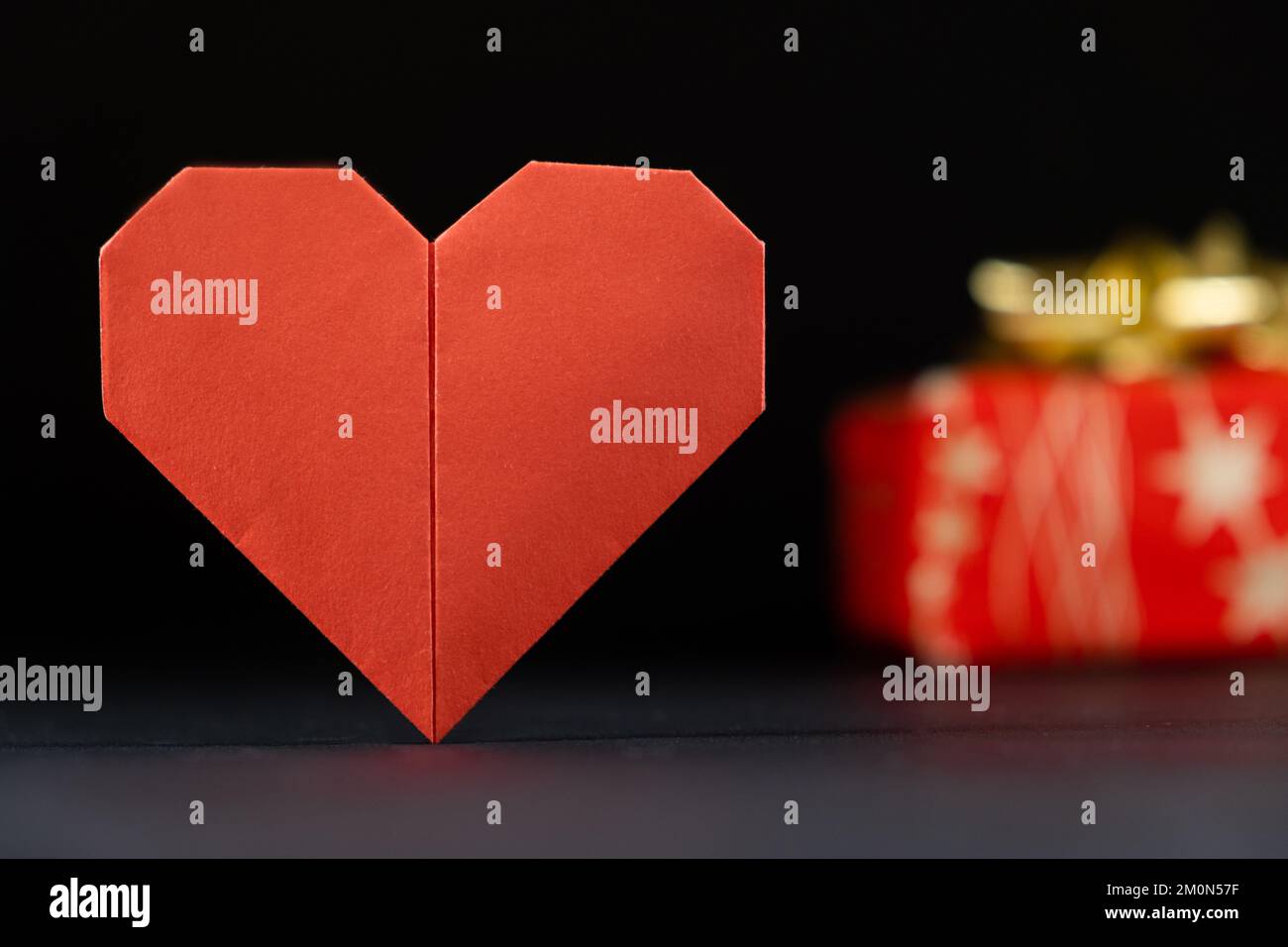Origami pour la Saint-Valentin - coeur en papier rouge et cadeau sur fond noir faites-le vous-même, bricolage. Banque D'Images
