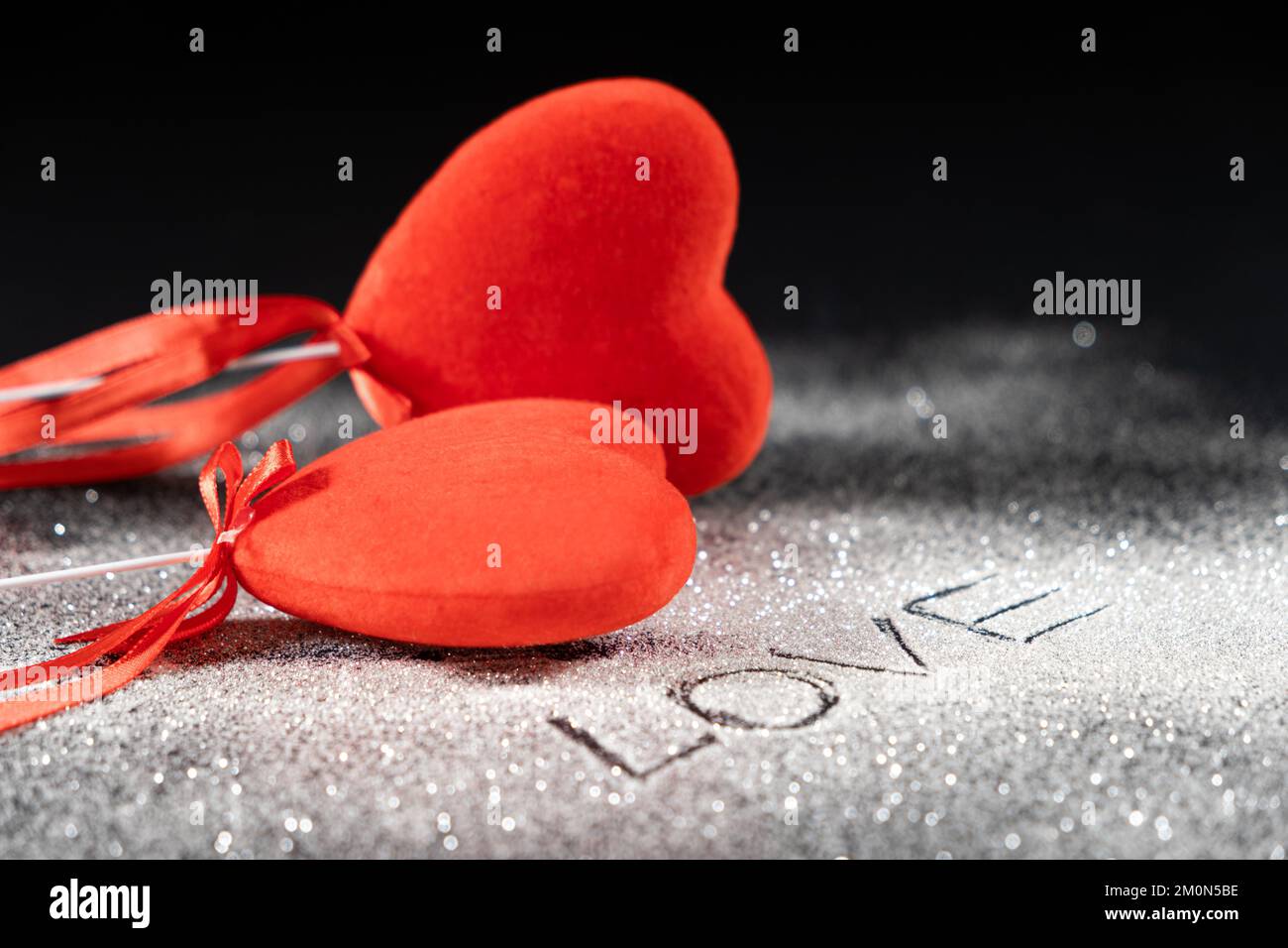 Saint-Valentin, deux coeurs rouges aimant sur fond noir avec des paillettes et le texte de l'amour. Banque D'Images