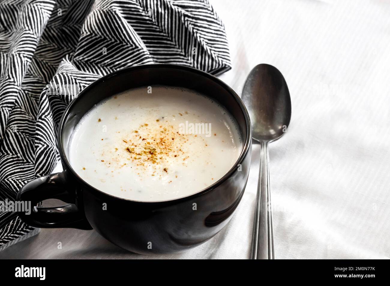 Soupe de chou-fleur (crème du Barry) dans un bol noir sur fond blanc avec tissu noir et blanc. Copier l'espace Banque D'Images Soupe de chou-fleur (crème du Barry) dans un bol noir sur fond blanc avec tissu noir et blanc. Copier l'espace Banque D'Images