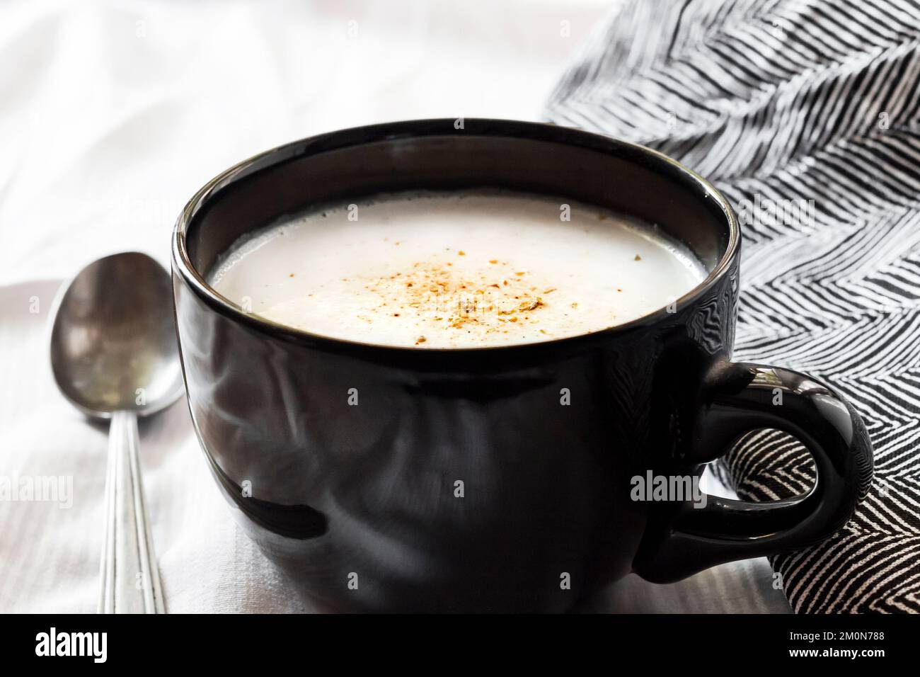Soupe de chou-fleur (crème du Barry) dans un bol noir sur fond blanc avec tissu noir et blanc. Banque D'Images Soupe de chou-fleur (crème du Barry) dans un bol noir sur fond blanc avec tissu noir et blanc. Banque D'Images