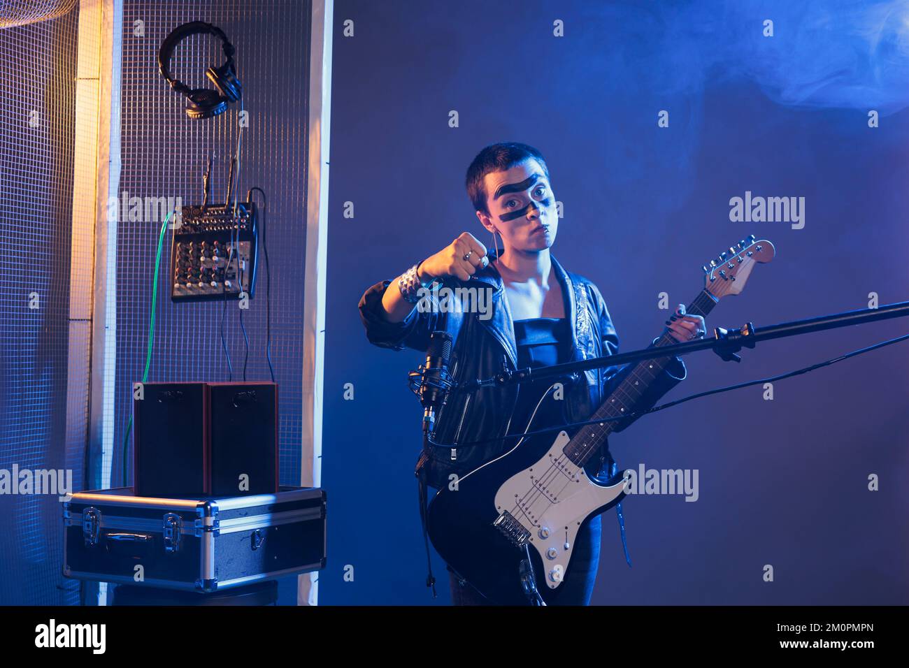 Crazy Rocker fou montrant le poing serré en studio avec de la fumée, agissant violent et étant agressif. Artiste de métal lourd chantant de la musique alternative avec de la guitare, étant en colère et faisant la menace. Banque D'Images