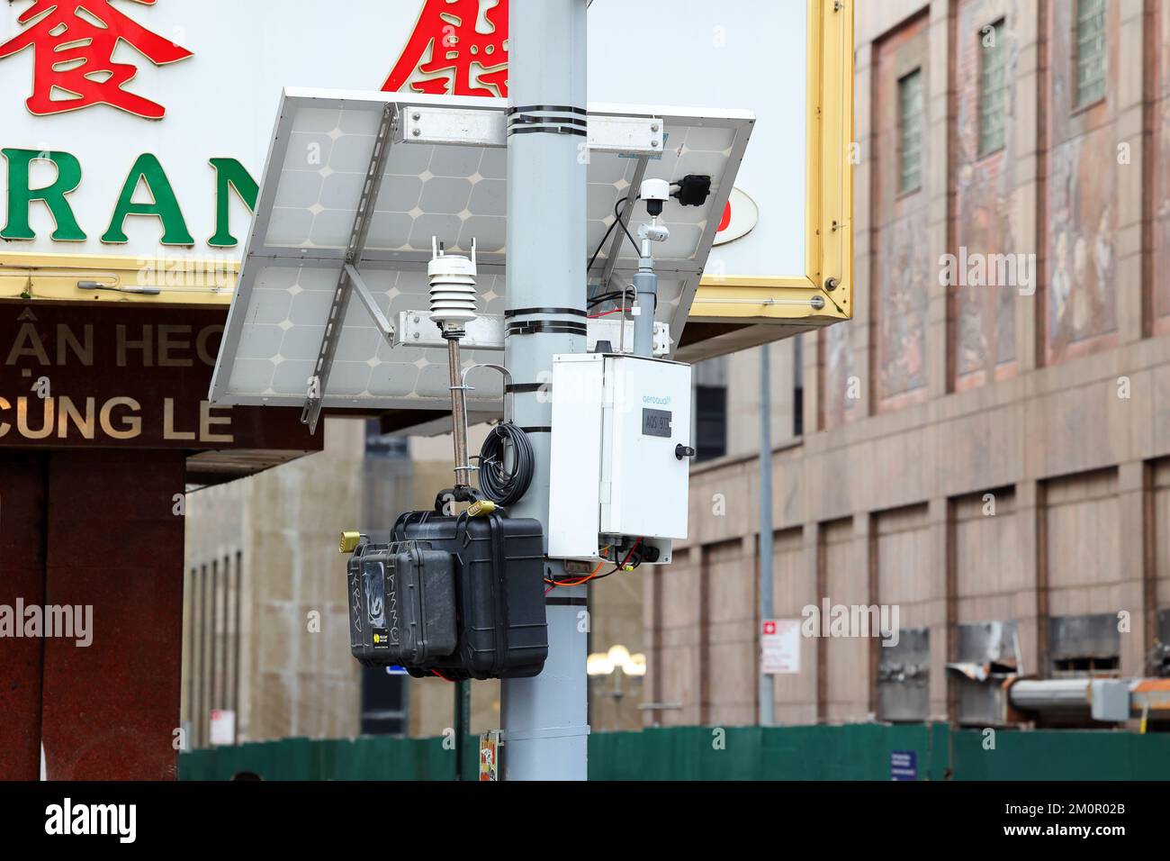 Une station de surveillance de l'air à énergie solaire montée sur un poteau de service public près de la démolition du complexe de détention de Manhattan dans le quartier chinois de Manhattan, New York. Banque D'Images