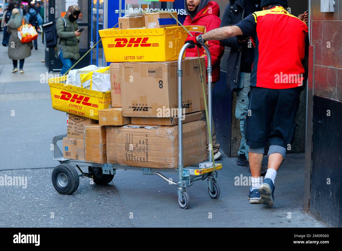 Un livreur DHL entre dans un bâtiment de Midtown Manhattan avec un camion plein de colis. Banque D'Images