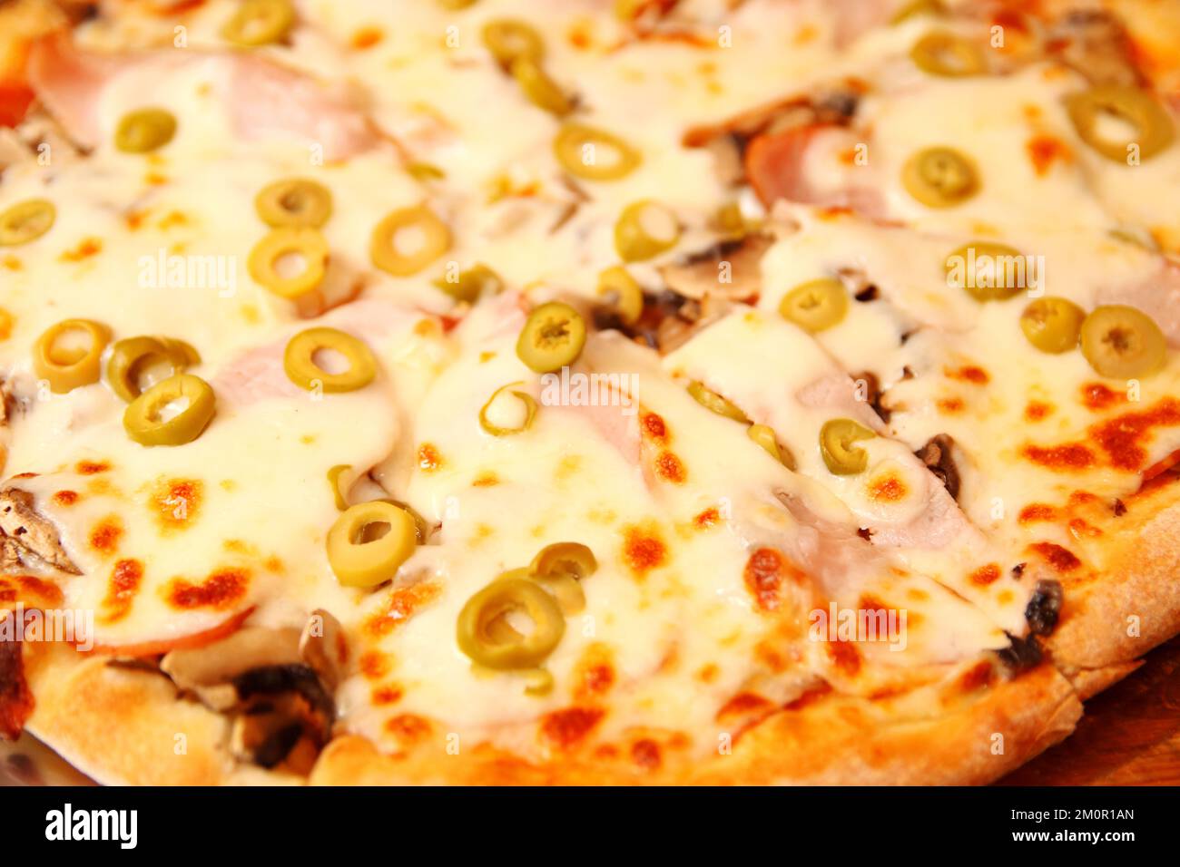 Refocalisation sur le fond de la pizza italienne avec des olives vertes. Tortilla avec mozzarella râpée. Pizza aux olives, basilic et fromage en gros plan. Pizzeria à l'extérieur Banque D'Images