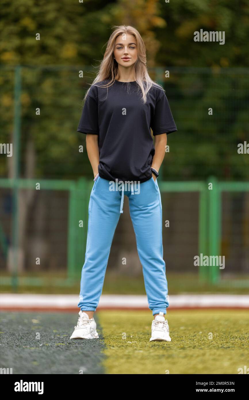 Femme blonde athlétique dans des vêtements surdimensionnés posant à l'extérieur Banque D'Images