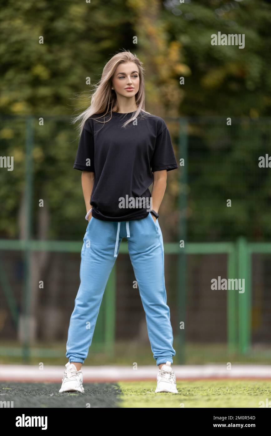 Mettre la femme blonde dans de grands vêtements posant à l'extérieur Banque D'Images