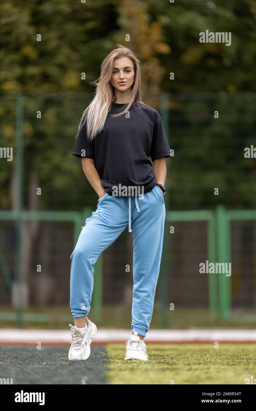 Femme blonde sportive dans des vêtements surdimensionnés posant à l'extérieur Banque D'Images