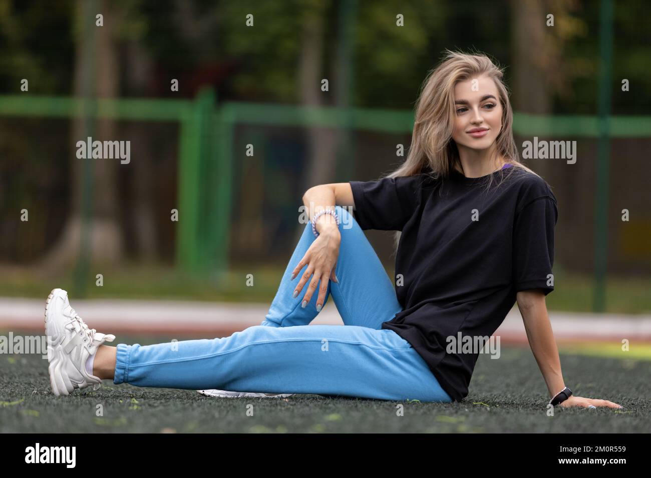 Mettre la femme blonde dans de grands vêtements posant à l'extérieur Banque D'Images