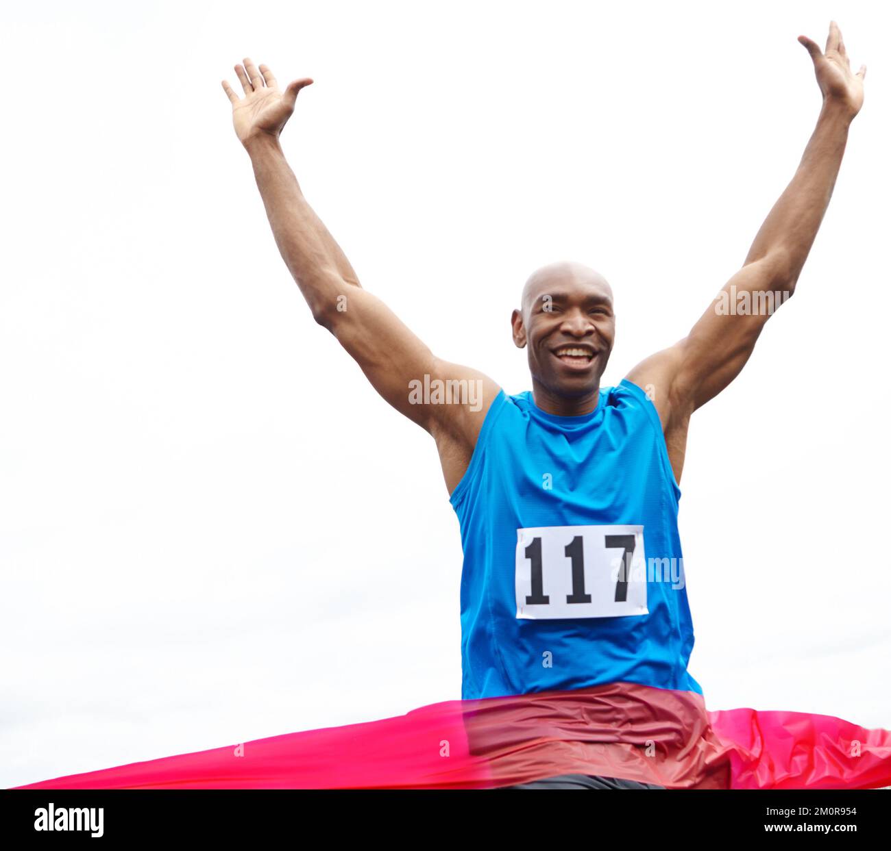 Célébrant sa victoire. Vue courte d'un athlète masculin gagnant une course avec ses bras relevés et un sourire sur son visage. Banque D'Images