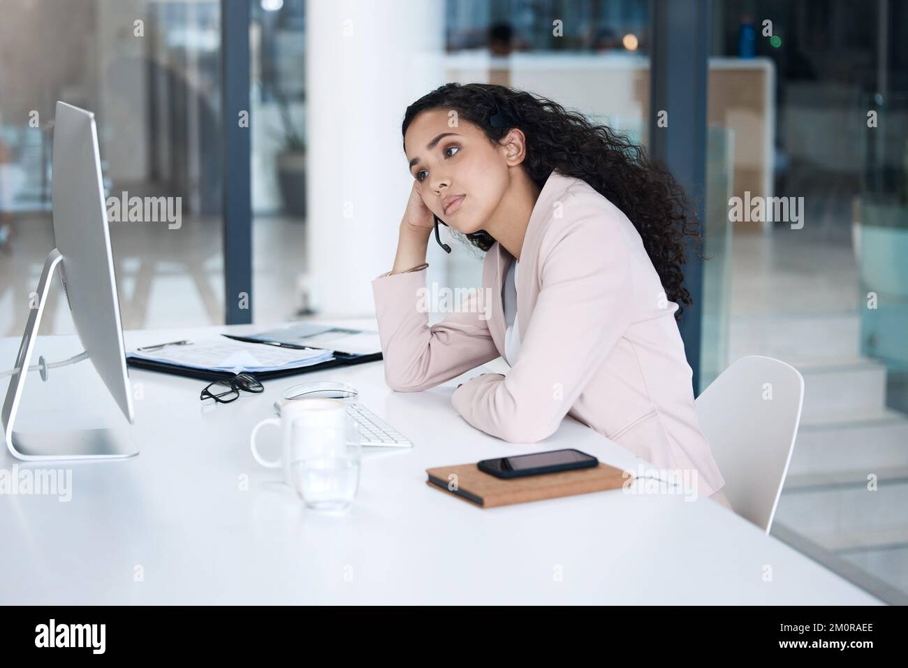 Jeune agent de centre d'appels de course mixte fatigué utilisant un ordinateur de bureau tout en portant un casque et en répondant aux appels. Employée du service client mécontent Banque D'Images