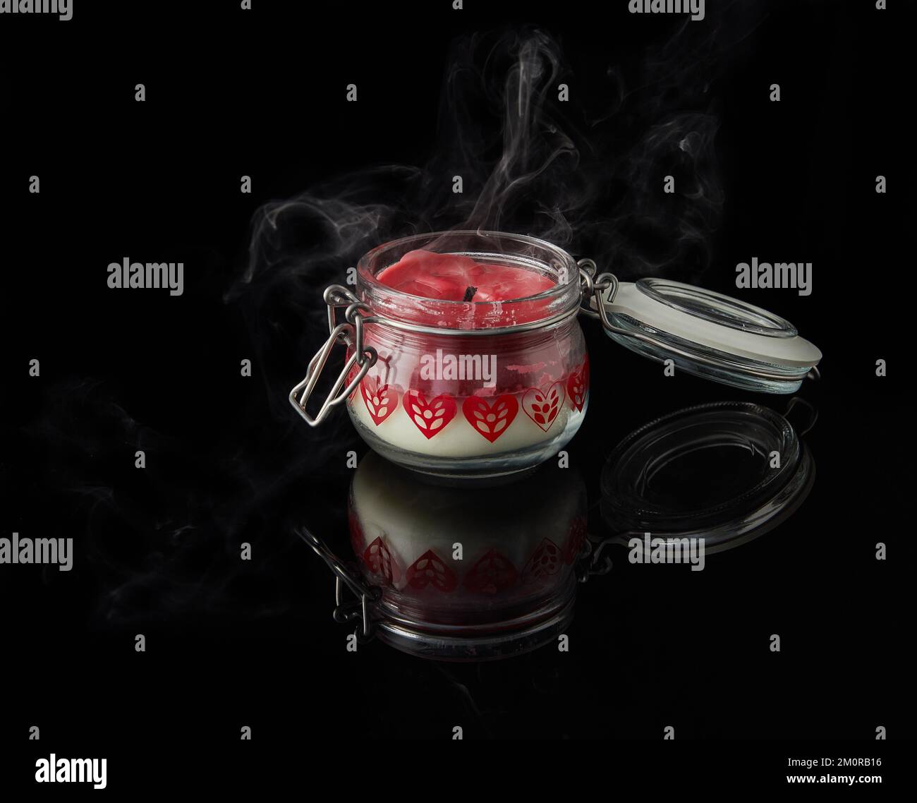 Une bougie éteinte avec fumée sur fond noir avec des arômes de vanille, de cerise, de grenade et de noix de coco. Banque D'Images