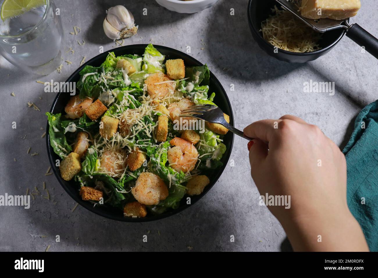 Gros plan de la femme mangeant de la salade César à la fourchette sur une table en marbre gris Banque D'Images