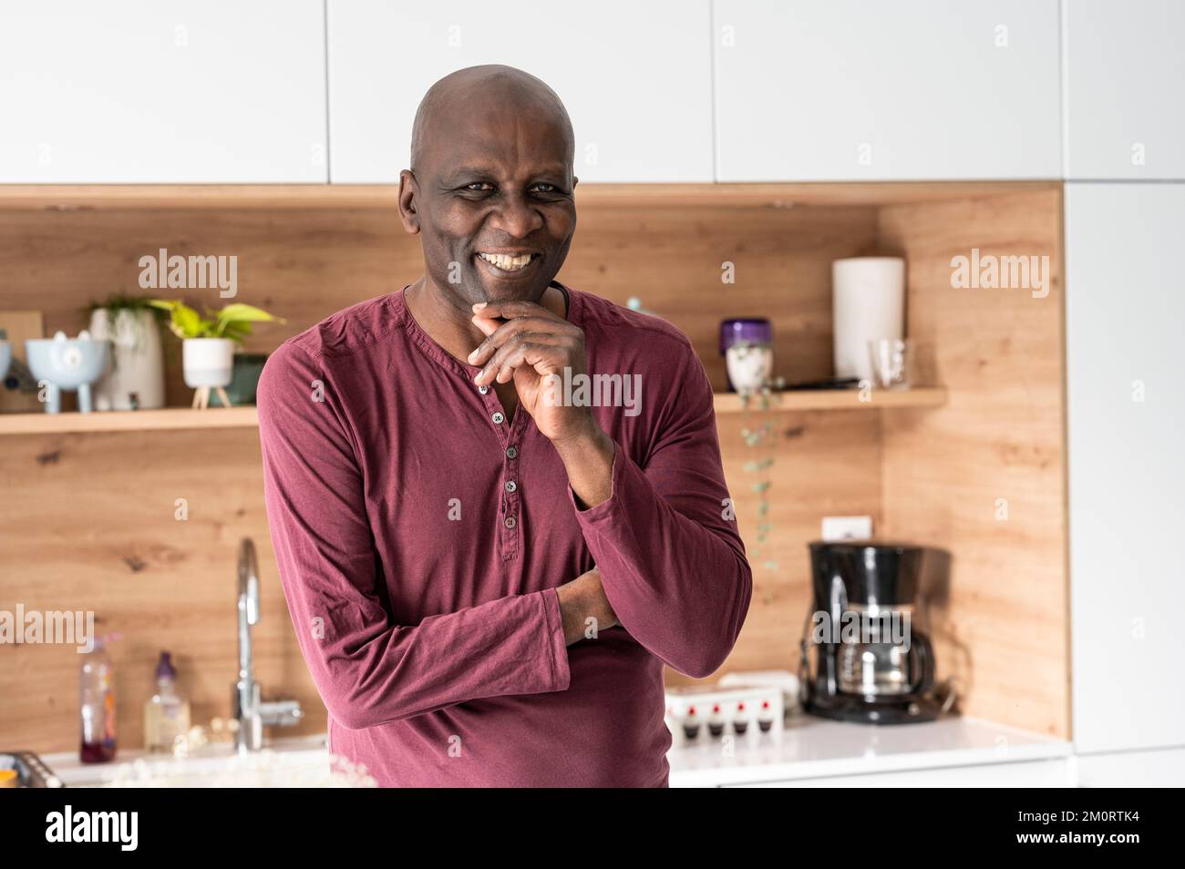 Portrait d'un homme afro-américain d'âge moyen souriant à la caméra tout en se tenant dans la cuisine Banque D'Images