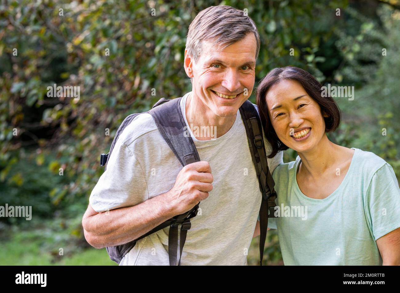 Couple diversifié d'âge moyen regardant la caméra tout en randonnant dans les bois Banque D'Images
