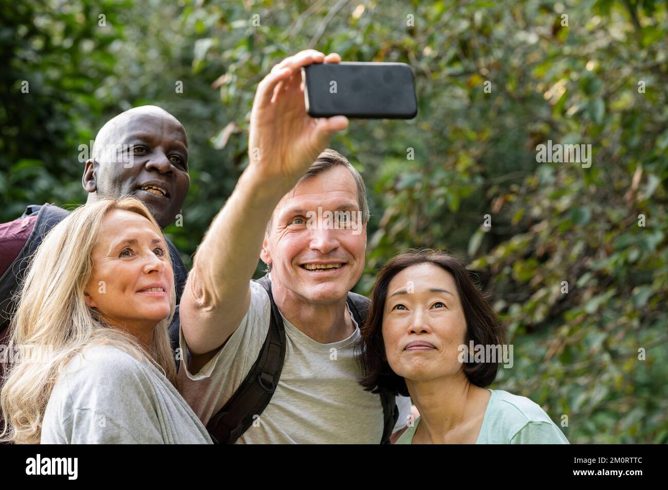 Amusant groupe diversifié d'amis d'âge moyen prenant un selfie dans le parc public Banque D'Images