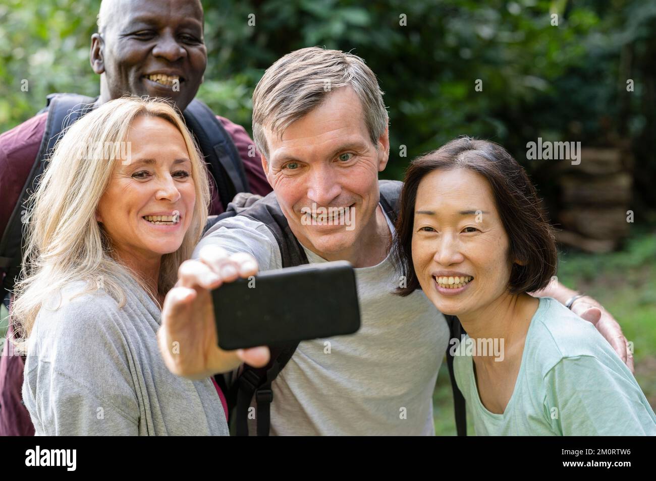 Amusant groupe diversifié d'amis d'âge moyen prenant un selfie dans le parc public Banque D'Images