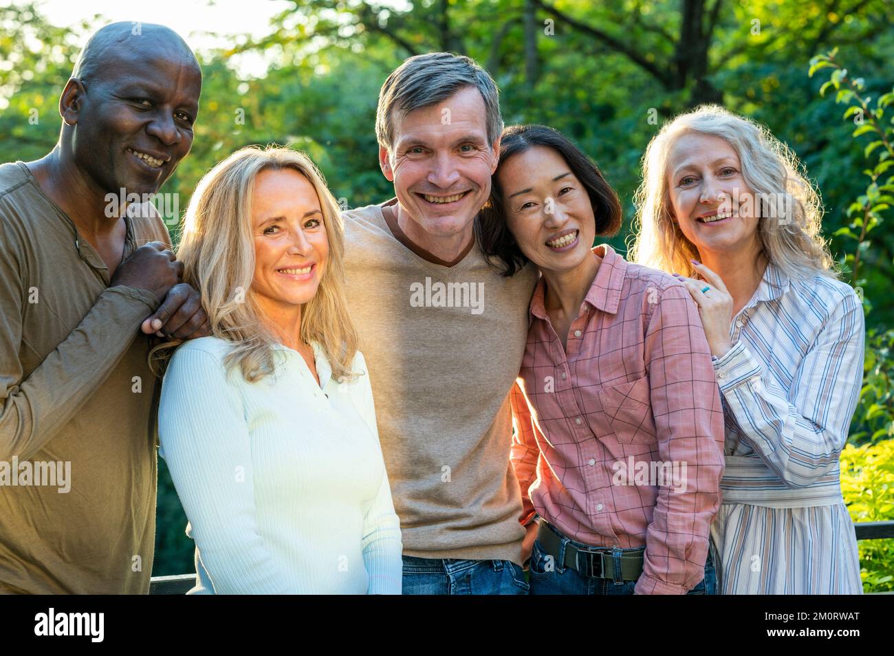 Groupe de divers amis seniors heureux posant pour la photo à l'extérieur au coucher du soleil Banque D'Images