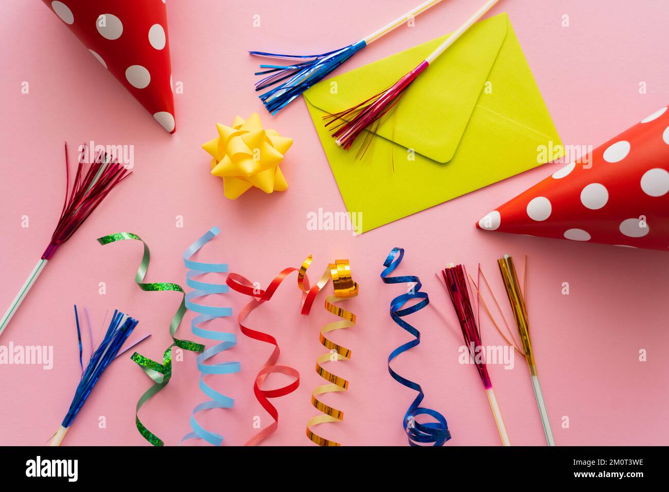 Vue de dessus de l'enveloppe près des capuchons de fête et de la serpentine sur fond rose, image de stock Banque D'Images