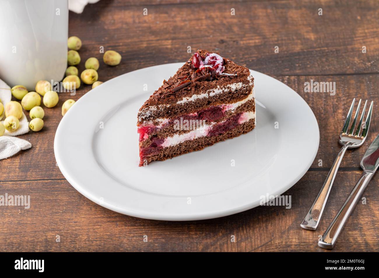 Gâteau à la cerise sur une assiette en porcelaine blanche sur une table en bois Banque D'Images