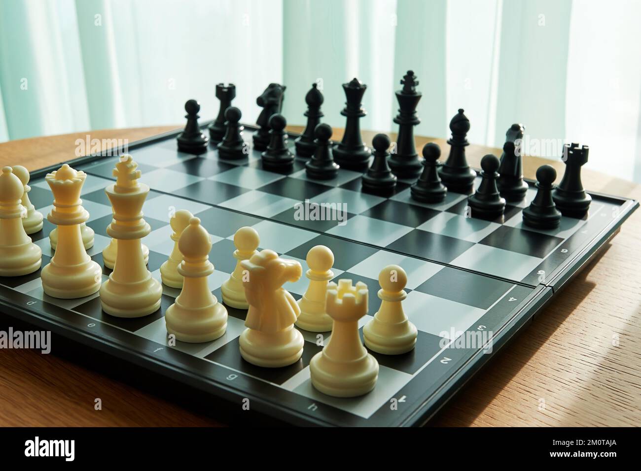 Jeu d'échecs sur la table en bois prêt pour le jeu dans la chambre près de la fenêtre. Concept de jeux intellectuels et d'activités de loisirs Banque D'Images