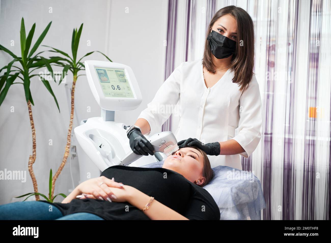 Kiev, Ukraine - 26 décembre 2020: Jeune esthéticienne faisant le nettoyage du visage pour le patient, en utilisant Ultraformer. Concept de procédure pour améliorer la peau pendant la période de quarantaine. Banque D'Images