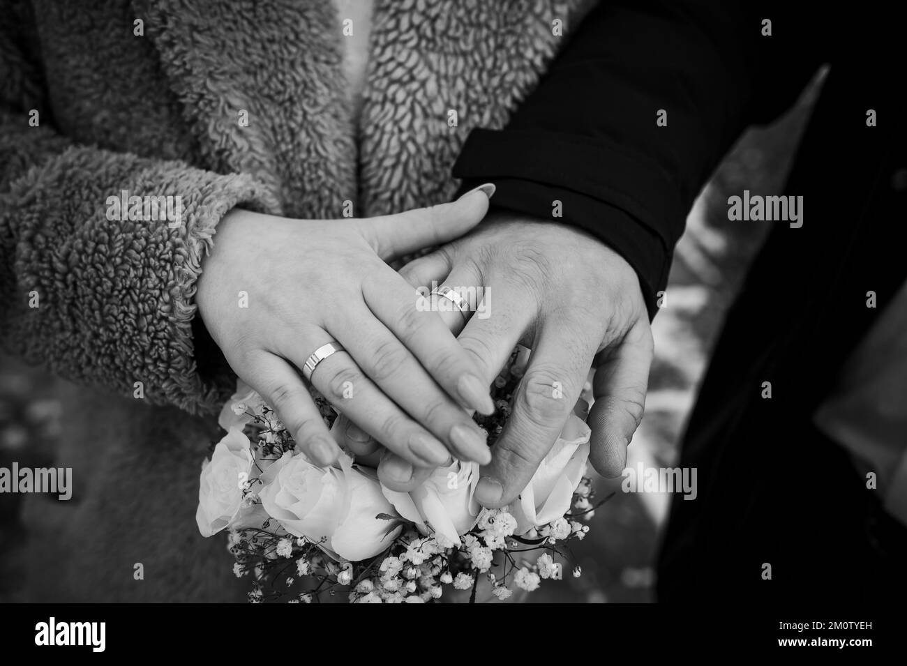 Mains des jeunes mariés avec anneaux de mariage sur le bouquet de mariage. Mains de la mariée et du marié sur un bouquet de fleurs. Banque D'Images