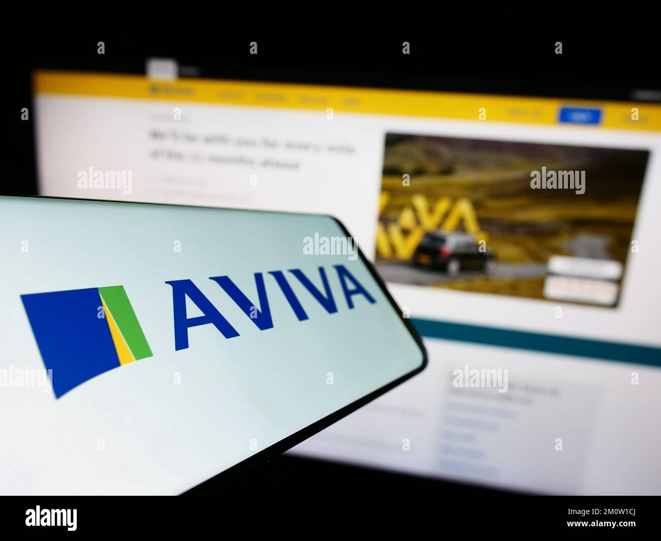 Téléphone portable avec logo de la compagnie d'assurance britannique Aviva plc à l'écran devant le site Web d'affaires. Mise au point au centre-gauche de l'écran du téléphone. Banque D'Images