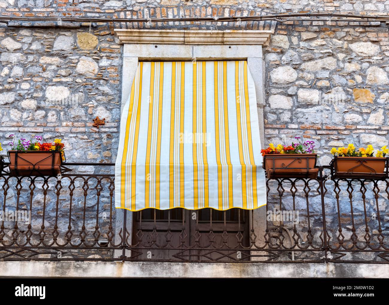 Taormina Sicile, stores rayés jaunes et blancs sur la balaconie en fer forgé Banque D'Images