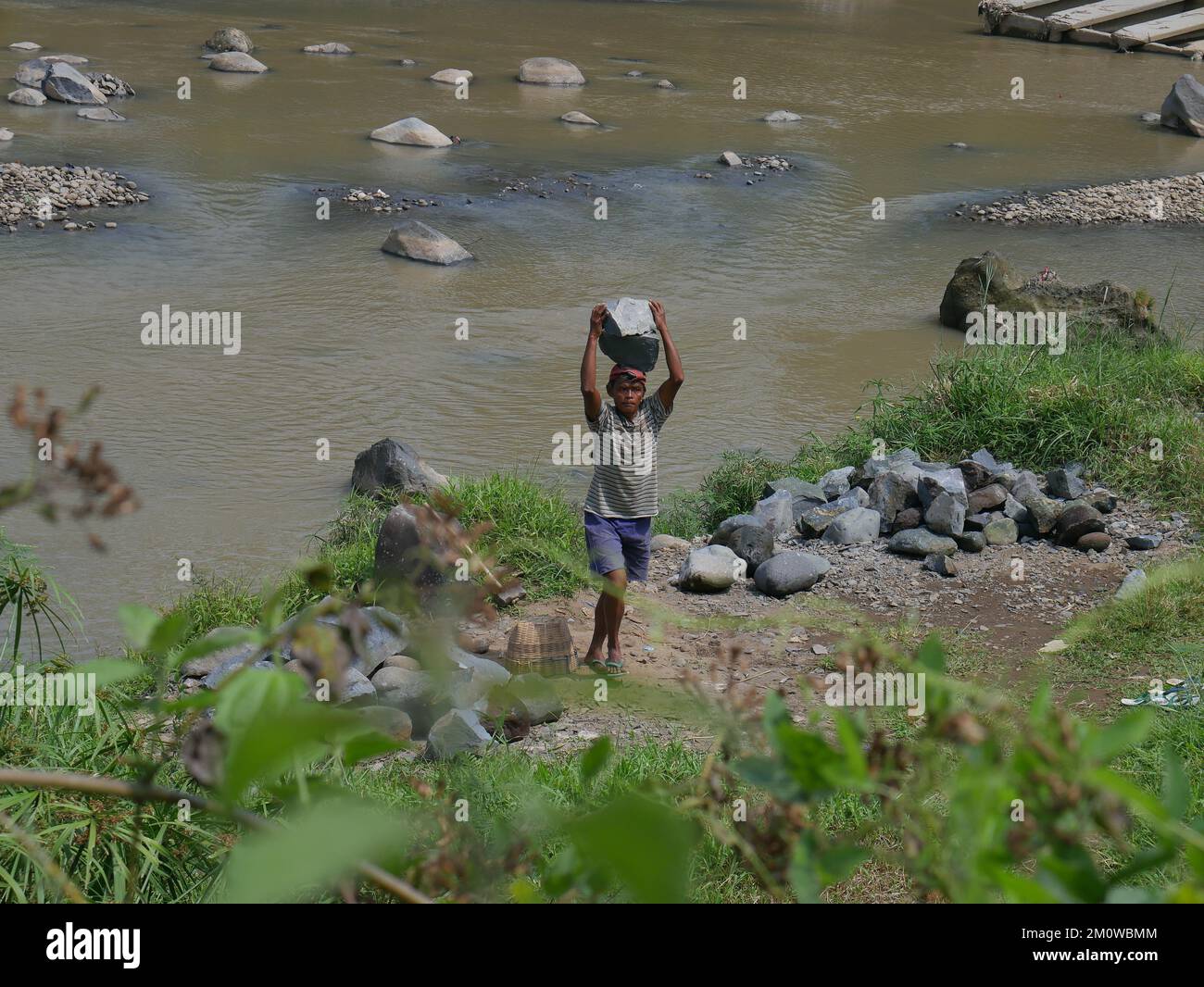 Les coolies traditionnelles prennent des pierres de la rivière pendant la journée pour les vendre comme matériaux de construction Banque D'Images