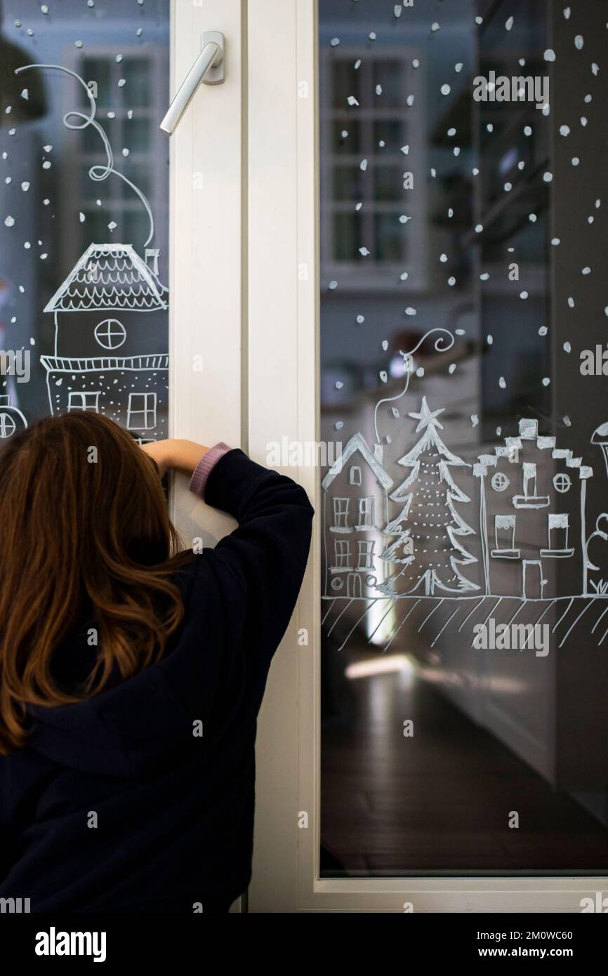 Petite fille caucasienne décorant la fenêtre de la maison pour Noël avec un  crayon blanc (craie liquide). Idée de décoration maison de fête. Plan  vertical, gros plan Photo Stock - Alamy