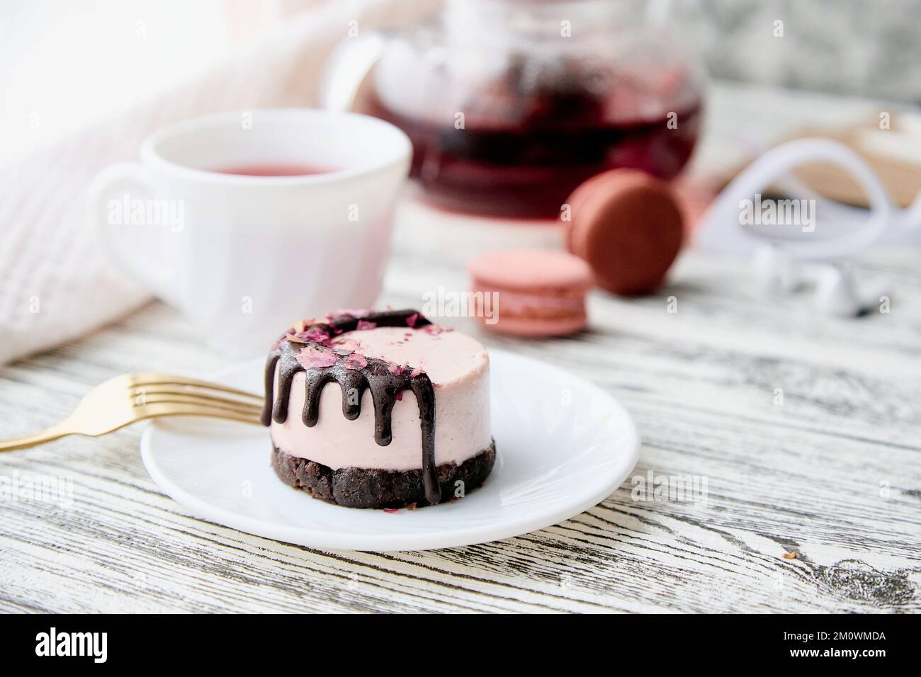 Petit-déjeuner féminin - rose sans pâtisserie gâteau à la framboise et tasse de thé. Dessert végétalien sain. Dîner romantique avec bougies. Banque D'Images