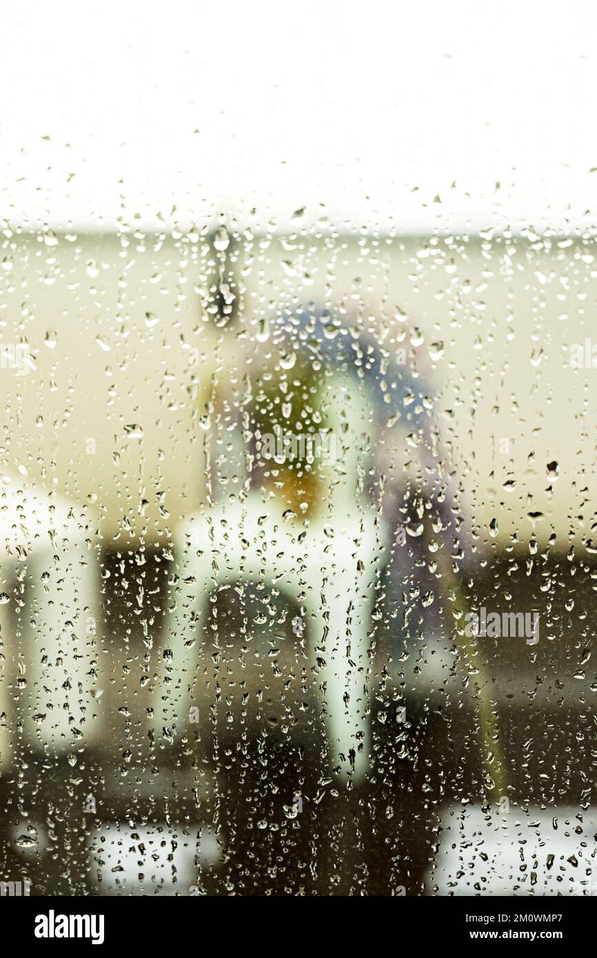Gouttes de pluie irrégulières glissant sur la surface en verre d'une fenêtre lors d'une journée de tempête Banque D'Images