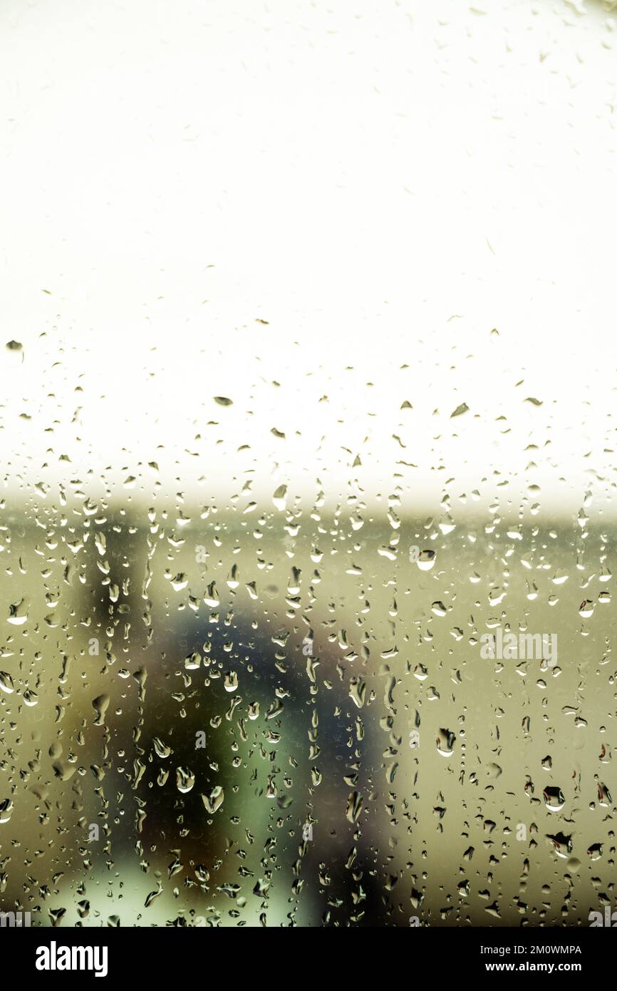 Gouttes de pluie irrégulières sur la surface en verre d'une fenêtre Banque D'Images