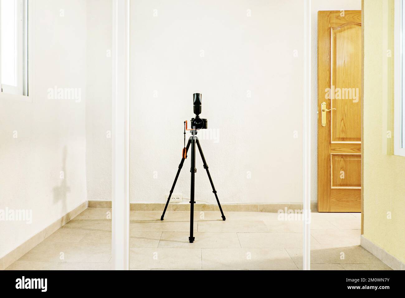 Un appareil photo autophotographié avec trépied et flash sur une porte miroir coulissante d'une armoire intégrée Banque D'Images