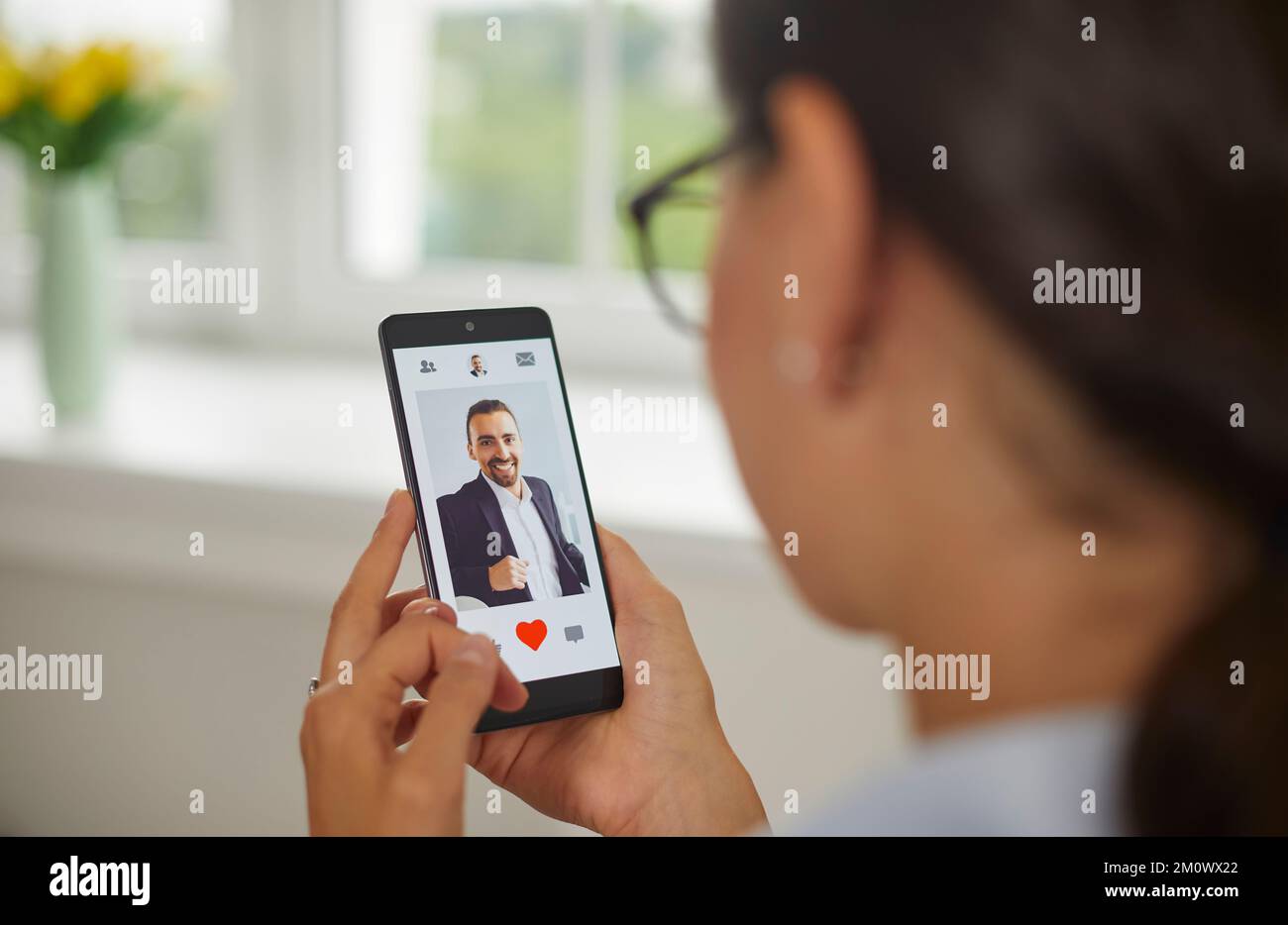 Jeune femme va donner un comme à la photo de l'homme dans l'application mobile de rencontres sur l'écran de smartphone. Banque D'Images