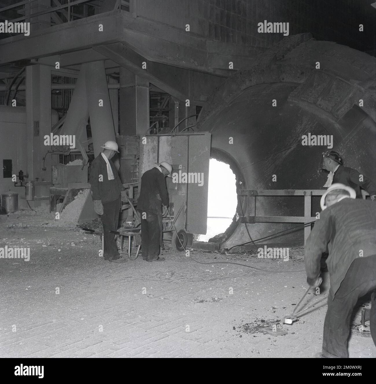 1950s, historique, aciéries, deux aciéries dans un four, debout derrière une garde de protection, l'une tenant une barre d'acier dans le four, Abbey Works, Port Talbot, pays de Galles du Sud, Royaume-Uni. Banque D'Images