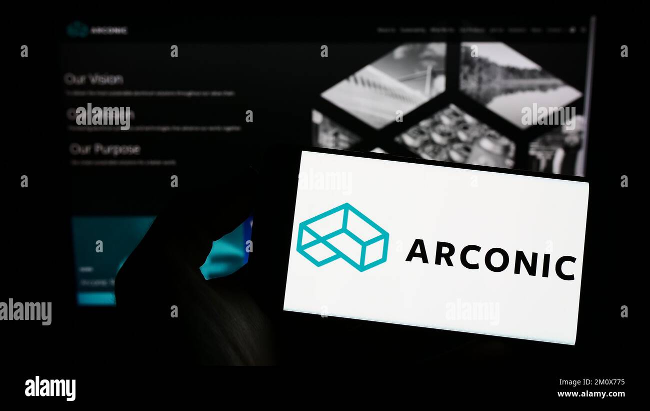 Personne tenant un téléphone portable avec le logo de la société américaine de métaux Arconic Corporation à l'écran en face de la page Web. Mise au point sur l'affichage du téléphone. Banque D'Images