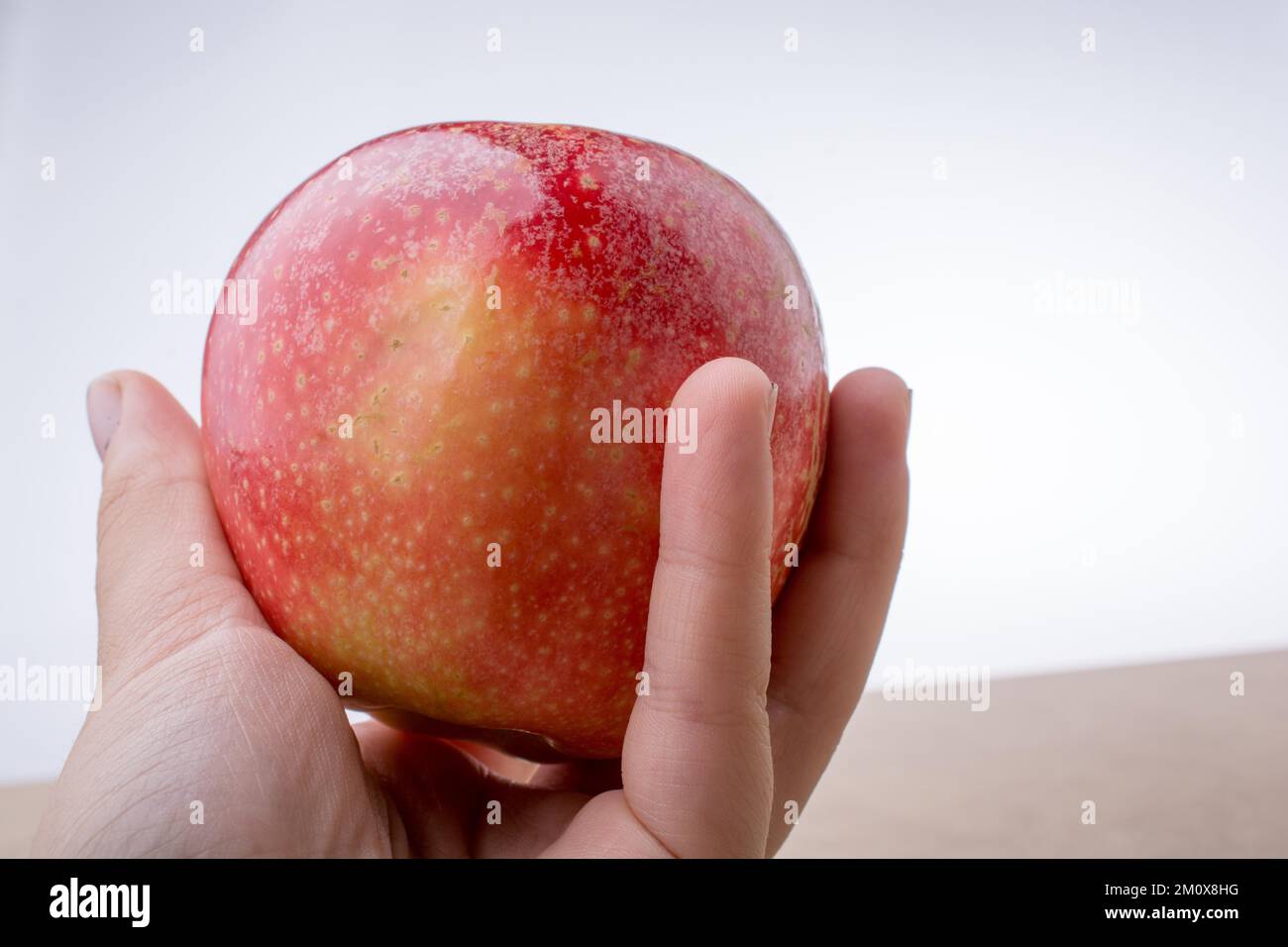 Main tenant une pomme rouge sur un bois Banque D'Images