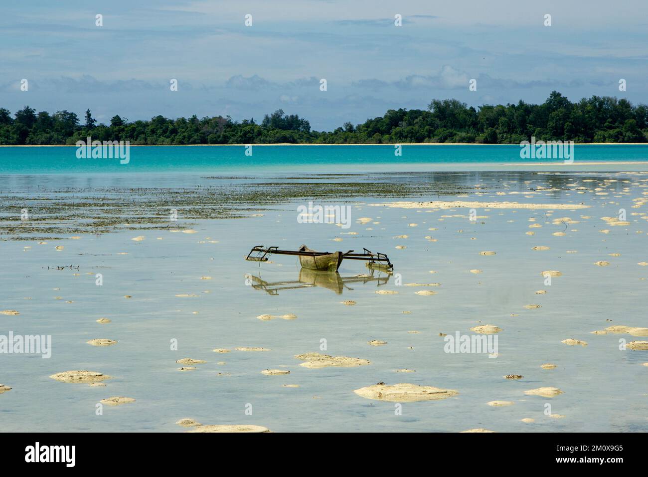 Un petit canoë sur une étendue de sable blanc avec une toile de fond étonnante de la mer verte de Tosca dans le sud de Halmahera, le nord de Maluku, Indonésie. Banque D'Images