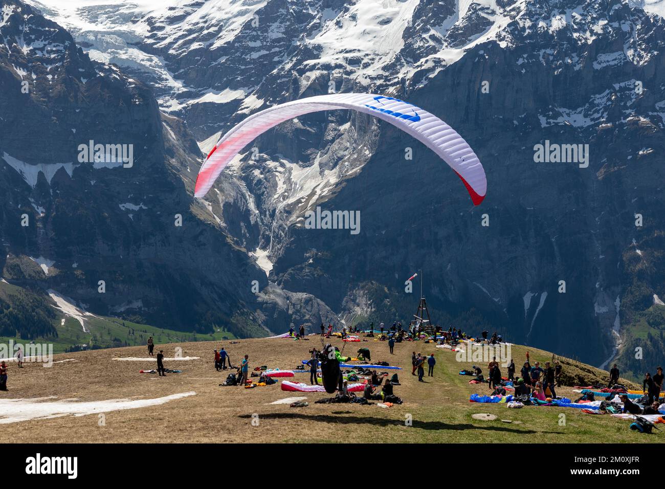 Un seul parapente prêt à faire un décollage au premier pic de montagne dans les Alpes suisses. D'autres regardent. Près de Grindelwald Banque D'Images