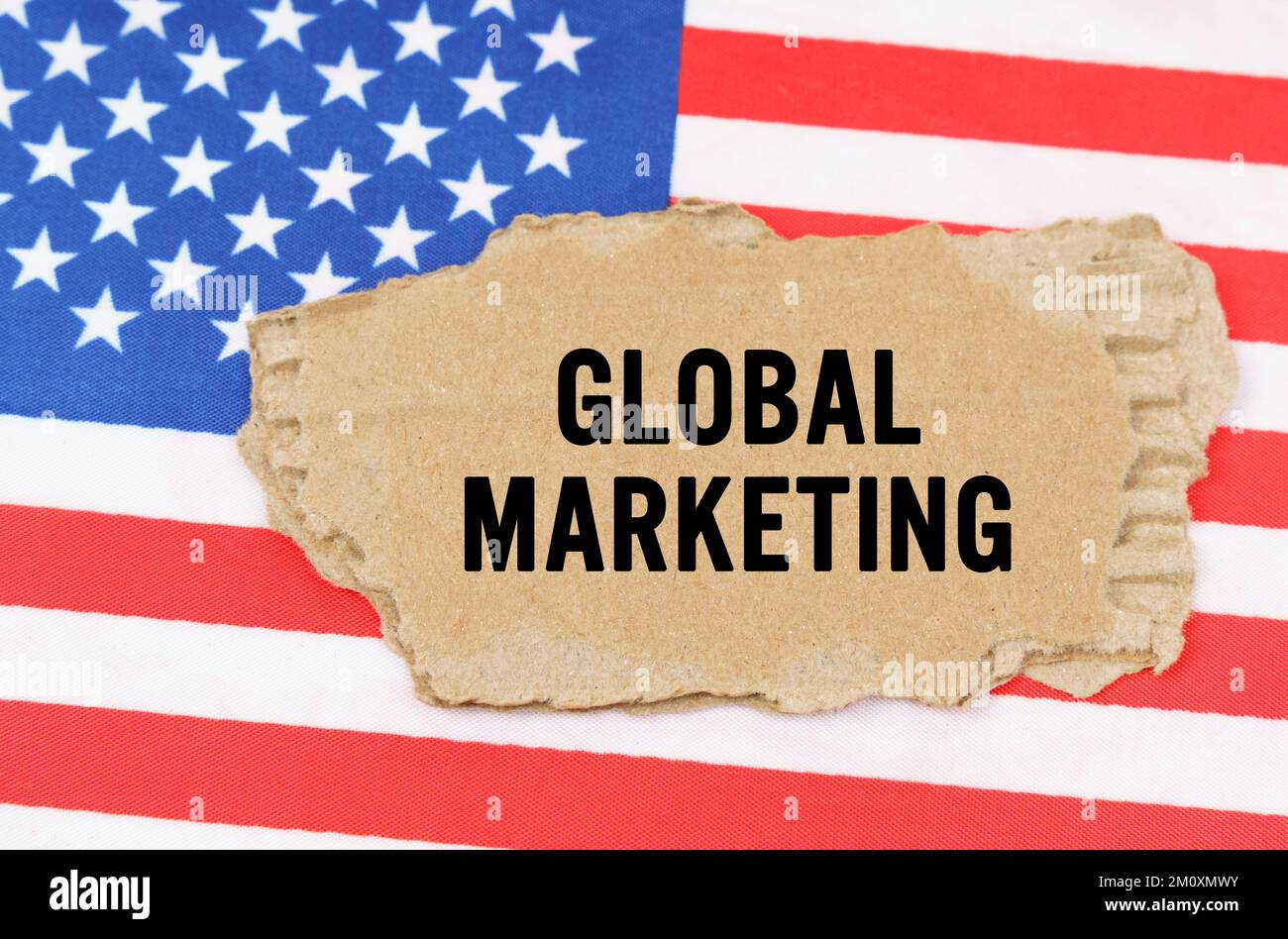 Concept commercial et financier. Sur le drapeau américain se trouve une boîte en carton avec l'inscription - MARKETING GLOBAL Banque D'Images