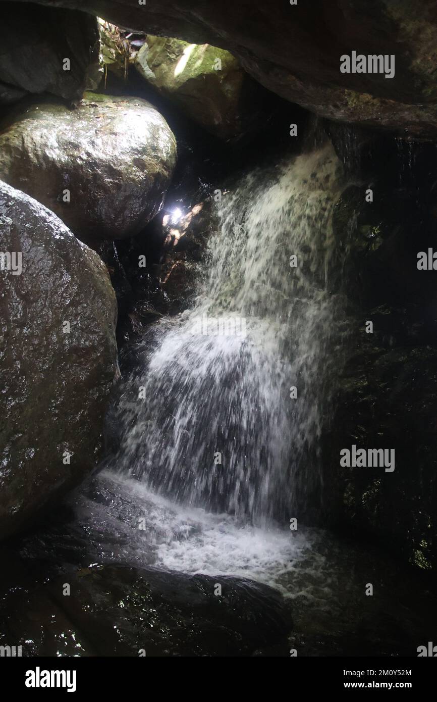 une grande cascade à côté d'un rocher dans l'ombre Banque D'Images