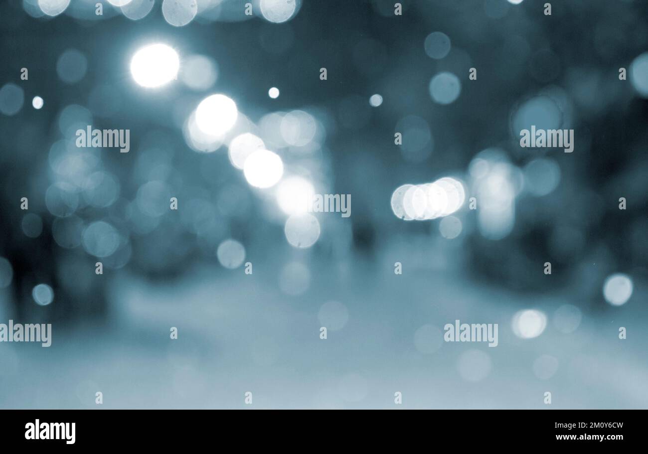 Résumé arrière-plan flou. Les gens qui marchent dans la rue des arbres de Noël décorés illuminés, illuminés et lumineux guirlandes dans la ville pendant les fortes chutes de neige la nuit d'hiver couleur bleue Banque D'Images