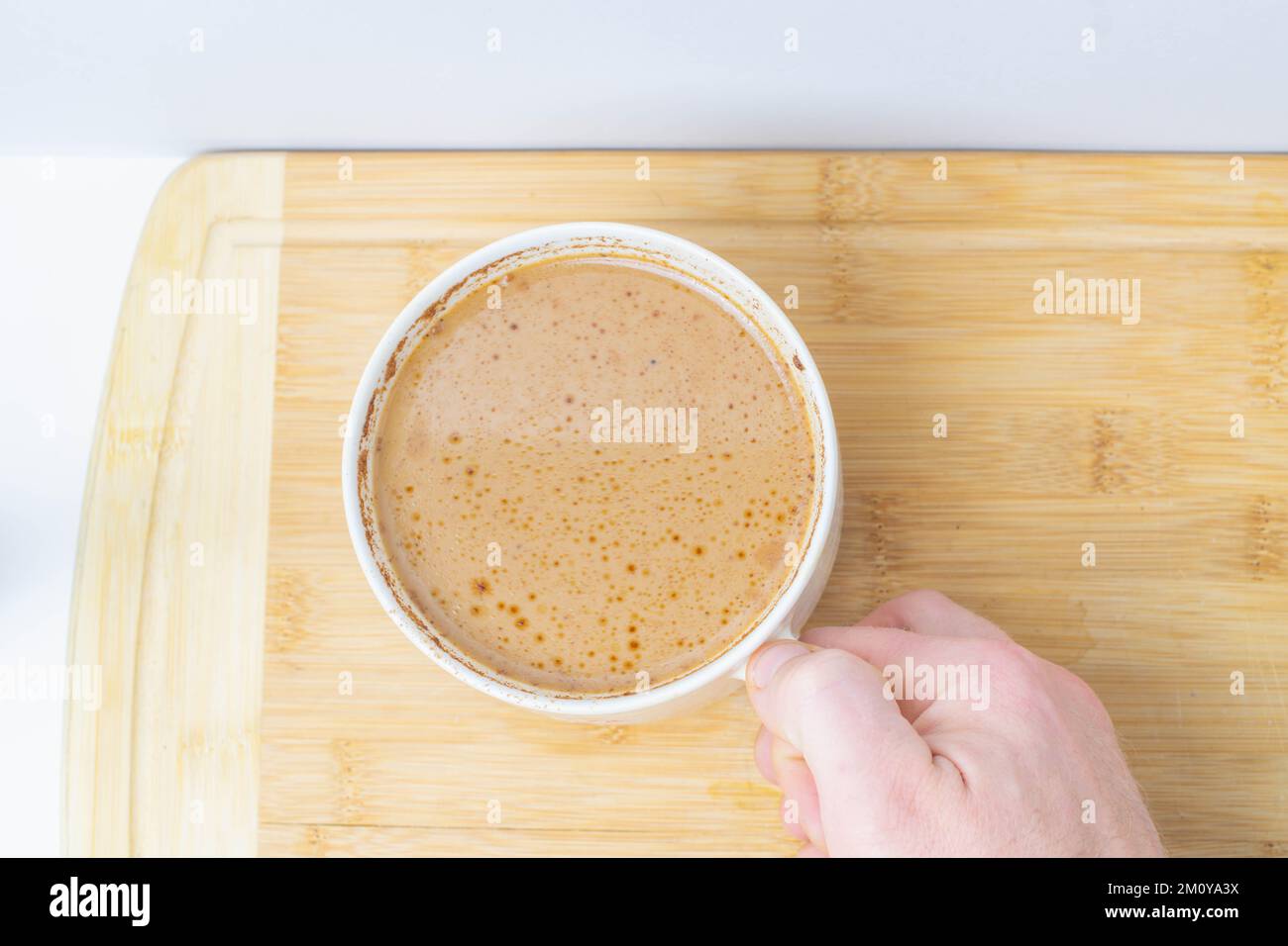 Café Keto dans une grande tasse avec de la cannelle, perspective de haut en bas d'une tasse et main le tenant. Banque D'Images