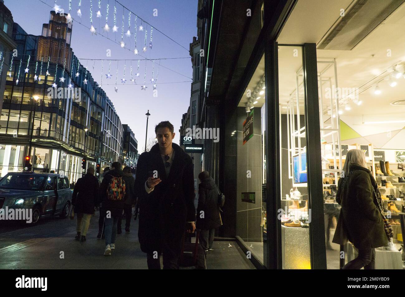 Londres, Royaume-Uni, 8 décembre 2022 : les lumières de Noël illuminent le ciel du coucher du soleil à la tombée de la nuit sur Oxford Street dans le West End. Les consommateurs affluent dans la rue malgré les inquiétudes sur la confiance des consommateurs pendant la crise du coût de la vie. Anna Watson/Alay Live News Banque D'Images