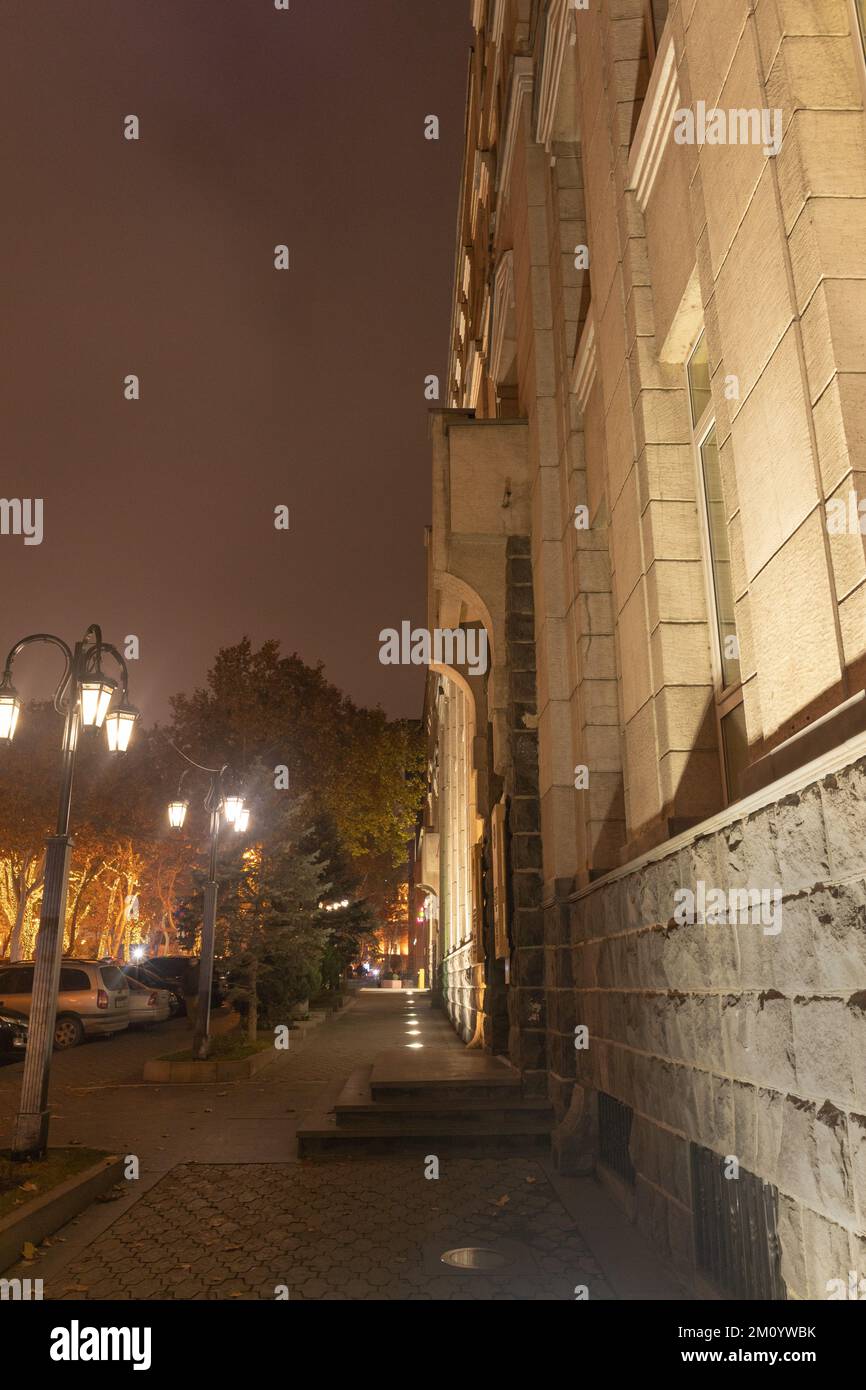 Chaussée vide avec bornes de lampe à la lumière chaude, un soir d'hiver. Projecteurs montés au sol, émettant de la lumière du bas vers le haut Banque D'Images