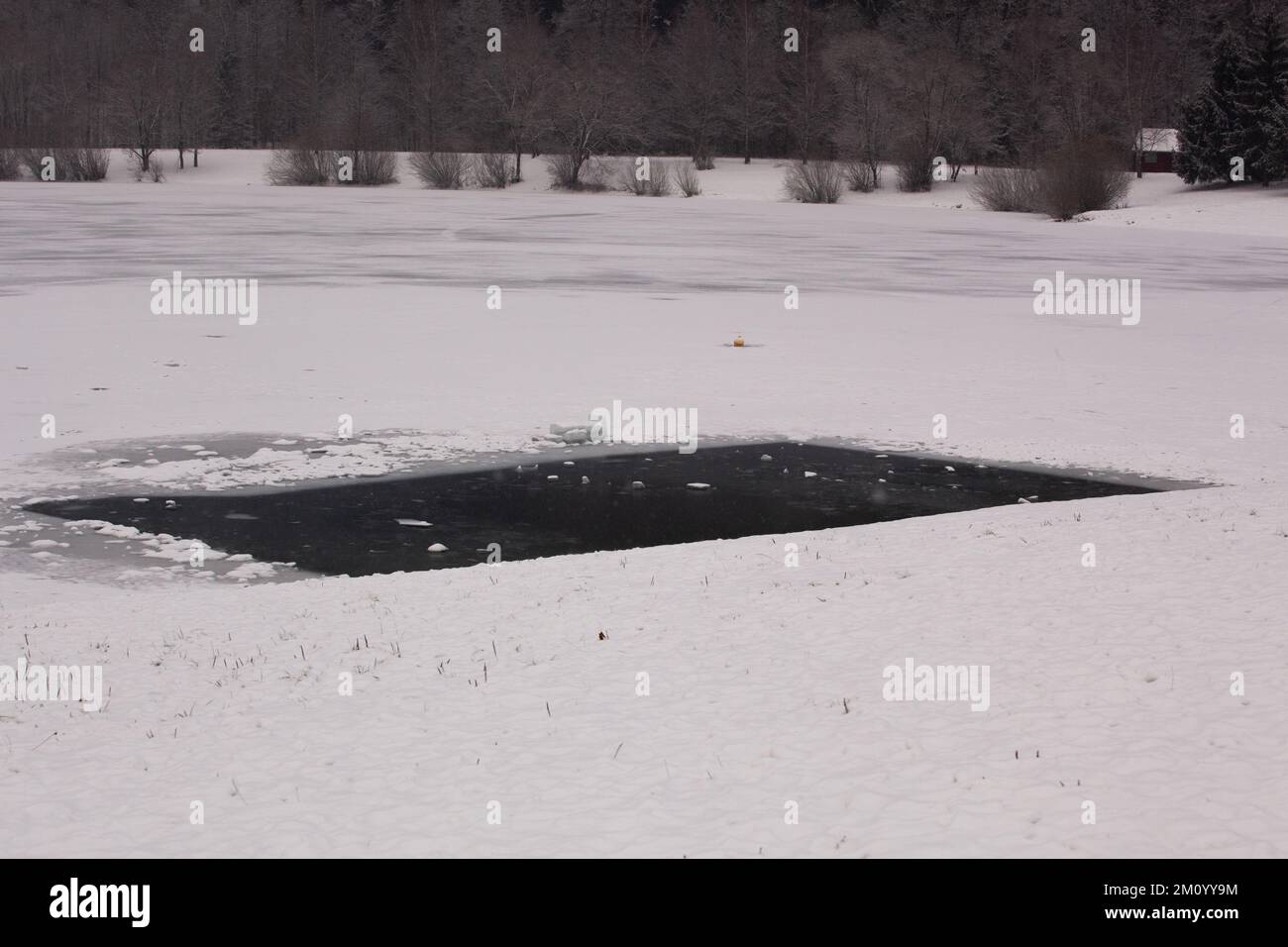 Un trou rectangulaire a été fait dans la glace épaisse couvrant un lac complètement gelé afin que le poisson puisse respirer et être nourri. Banque D'Images