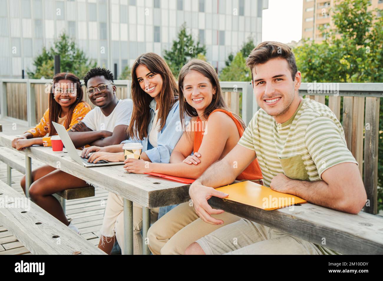 Groupe multiracial d'adolescents heureux regardant la caméra, souriant détendu ensemble à l'extérieur du campus de l'université prenant une pause. Réunion de jeunes et de gens d'université amusant appréciant la lumière du soleil étudiant et posant dans l'attitude positive à l'extérieur. Concept d'éducation. Photo de haute qualité Banque D'Images