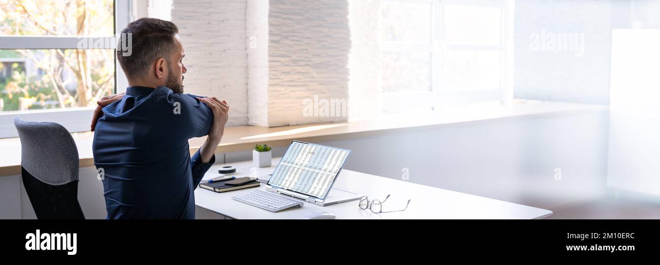 Employé s'étendant au bureau au travail Banque D'Images