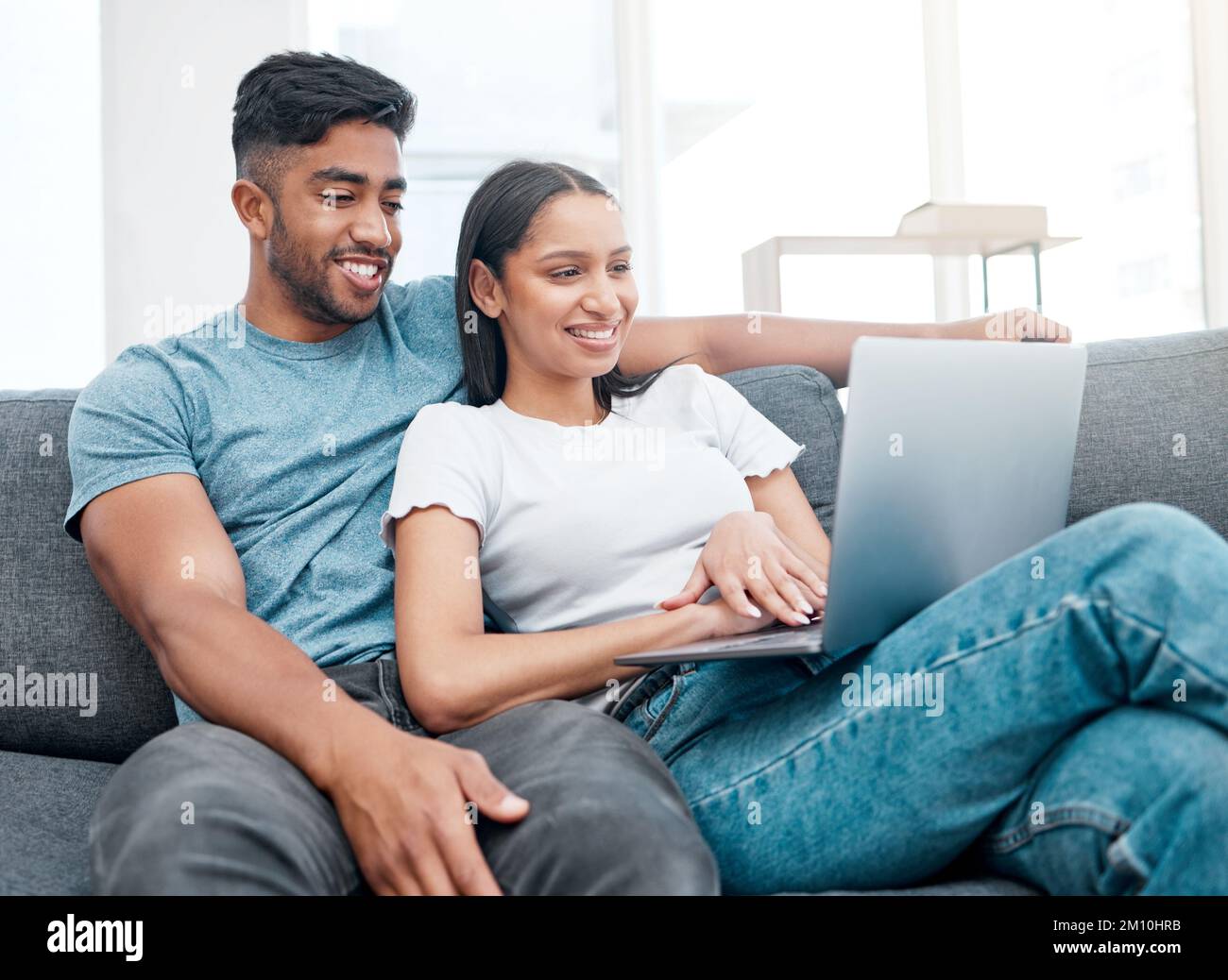 Faire une pause cinéma. un jeune couple assis sur le canapé dans sa nouvelle maison et utilisant un ordinateur portable. Banque D'Images